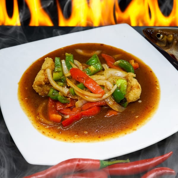 Thai sweet and sour fish with bell peppers and onions, with a fish head and chili peppers.