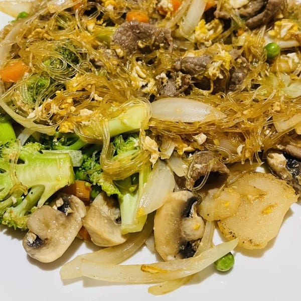 Close-up of Thai glass noodles with beef, broccoli, mushrooms, onions, and carrots.